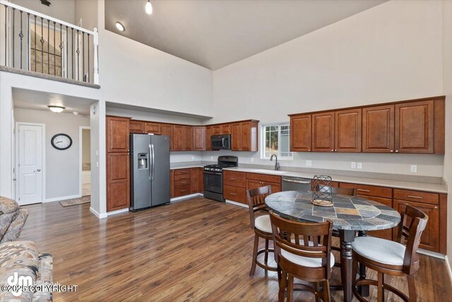 53578 Bell Ave, Nikiski/North Kenai, AK 99611 - kitchen featuring stainless steel appliances, high vaulted ceiling, a sink, light countertops, and dark wood-style flooring