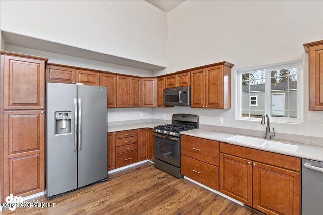 53578 Bell Ave, Nikiski/North Kenai, AK 99611 - kitchen with stainless steel appliances, a sink, brown cabinetry, light countertops, and wood finished floors