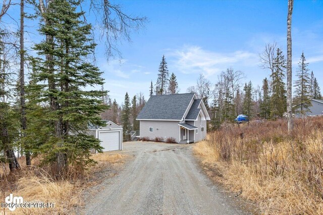 53578 Bell Ave, Nikiski/North Kenai, AK 99611 - view of property exterior featuring an outdoor structure, dirt driveway, a garage, and a shingled roof