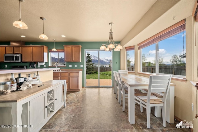 241 N Pasture Pl, Palmer, AK 99645 - kitchen with stainless steel microwave, hanging light fixtures, stone finish floors, a sink, and a mountain view