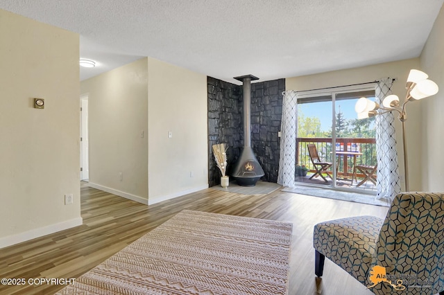 4640 Reka Dr Unit 19, Anchorage, AK 99508 - living area featuring wood finished floors, a wood stove, a textured ceiling, and baseboards
