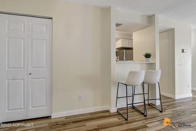 4640 Reka Dr Unit 19, Anchorage, AK 99508 - kitchen with freestanding refrigerator, wood finished floors, baseboards, and white cabinetry