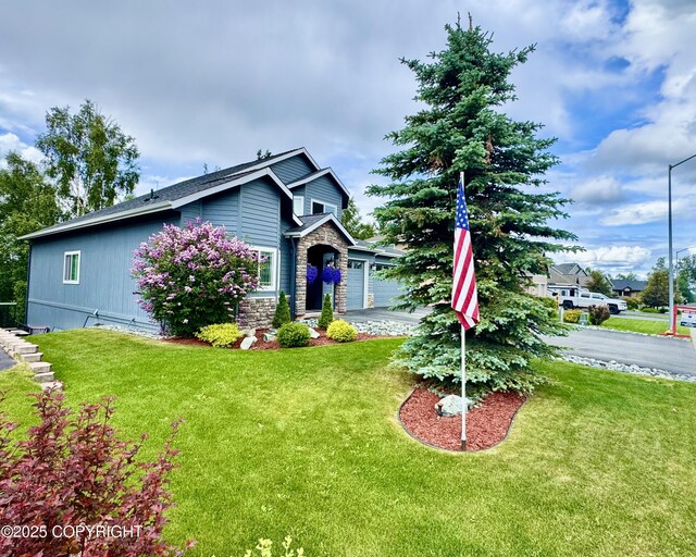 10885 Splendor Loop, Eagle River, AK 99577 - view of front of property with stone siding, a front lawn, and a garage