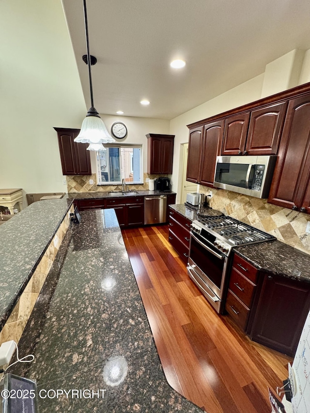 10885 Splendor Loop, Eagle River, AK 99577 - kitchen with appliances with stainless steel finishes, dark wood-type flooring, decorative backsplash, hanging light fixtures, and dark stone countertops