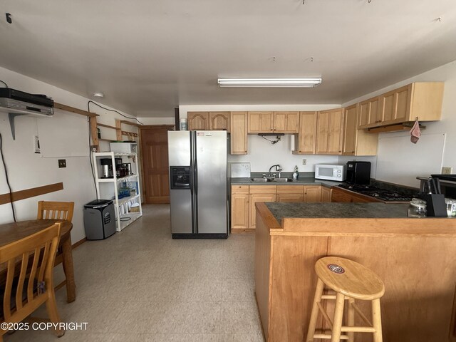 69290 Emily Ct, Ninilchik, AK 99556 - kitchen featuring stainless steel refrigerator with ice dispenser, white microwave, a sink, dark countertops, and a peninsula