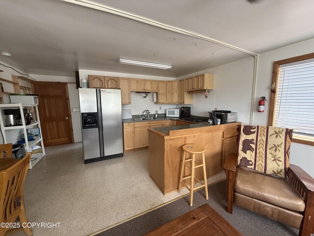 69290 Emily Ct, Ninilchik, AK 99556 - kitchen with stainless steel refrigerator with ice dispenser, a sink, white microwave, dark countertops, and a breakfast bar
