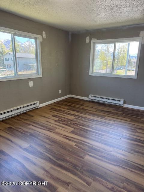 180 Grand Larry St Unit B6, Anchorage, AK 99504 - empty room with a baseboard heating unit, a textured ceiling, wood finished floors, and baseboards