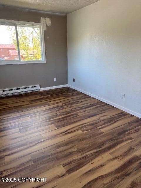 180 Grand Larry St Unit B6, Anchorage, AK 99504 - empty room featuring a baseboard radiator, baseboards, dark wood-style flooring, and a textured ceiling