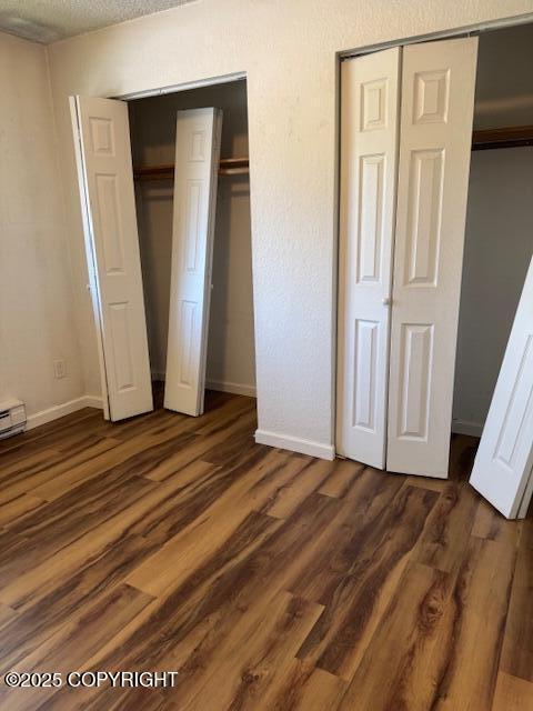 180 Grand Larry St Unit B6, Anchorage, AK 99504 - unfurnished bedroom with dark wood finished floors, baseboards, and multiple closets