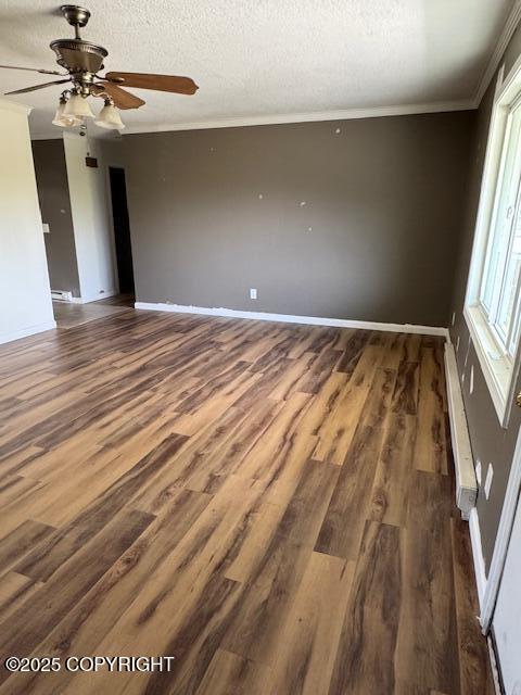 180 Grand Larry St Unit B6, Anchorage, AK 99504 - spare room featuring baseboard heating, ornamental molding, dark wood-style flooring, baseboards, and ceiling fan