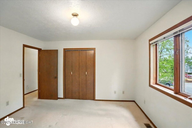 19254 Adak Cir, Eagle River, AK 99577 - unfurnished bedroom featuring baseboards, light colored carpet, a closet, and a textured ceiling