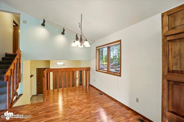 19254 Adak Cir, Eagle River, AK 99577 - unfurnished dining area featuring a chandelier, wood finished floors, stairway, and rail lighting