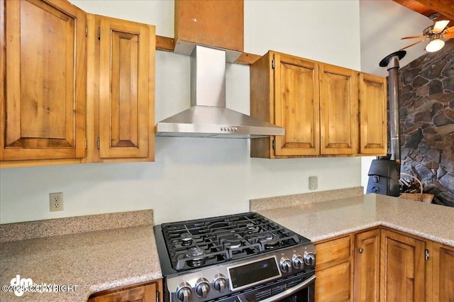 19254 Adak Cir, Eagle River, AK 99577 - kitchen featuring wall chimney exhaust hood, stainless steel range with gas cooktop, a wood stove, a ceiling fan, and light countertops