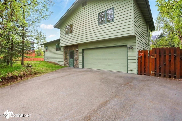 19254 Adak Cir, Eagle River, AK 99577 - view of property exterior with an attached garage, stone siding, and asphalt driveway