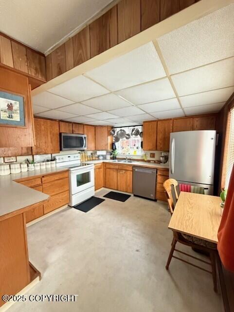 1411 Mission Rd, Kodiak, AK 99615 - kitchen featuring appliances with stainless steel finishes, a drop ceiling, concrete floors, light countertops, and brown cabinets