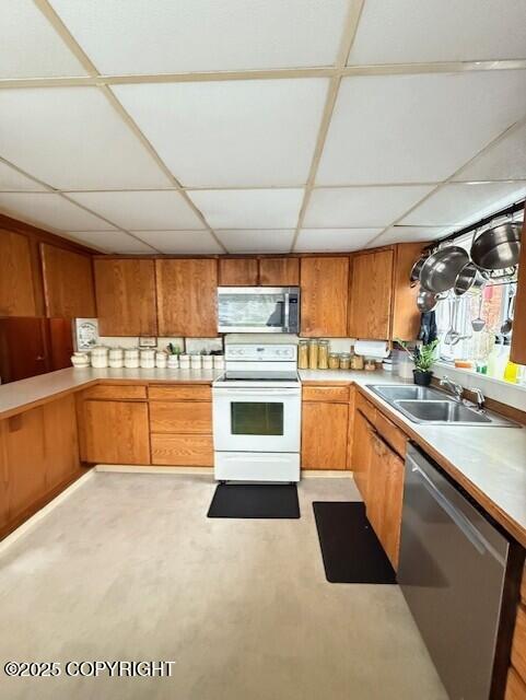 1411 Mission Rd, Kodiak, AK 99615 - kitchen featuring stainless steel appliances, a sink, a paneled ceiling, brown cabinets, and light countertops