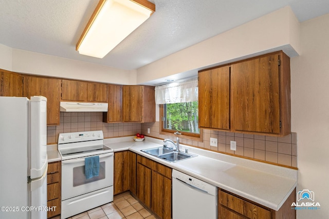 18113 Misty Falls Cir, Eagle River, AK 99577 - kitchen with white appliances, under cabinet range hood, a sink, brown cabinetry, and tasteful backsplash