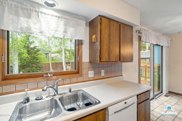 18113 Misty Falls Cir, Eagle River, AK 99577 - kitchen with a sink, dishwasher, brown cabinets, light countertops, and backsplash