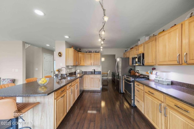 2823 Discovery Bay Dr, Anchorage, AK 99515 - kitchen with stainless steel appliances, a sink, a breakfast bar, light brown cabinetry, and dark wood finished floors