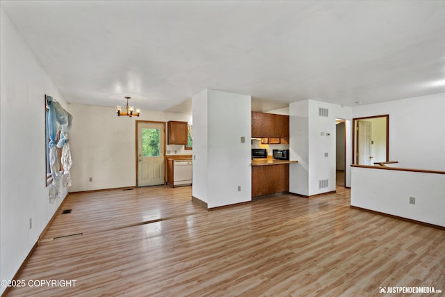 1031 E Dunedin St, Wasilla, AK 99654 - unfurnished living room with a chandelier, light wood finished floors, and baseboards