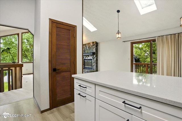 2921 Rocky Bay Cir, Anchorage, AK 99515 - kitchen with a skylight, light wood-style floors, white cabinets, pendant lighting, and light stone counters