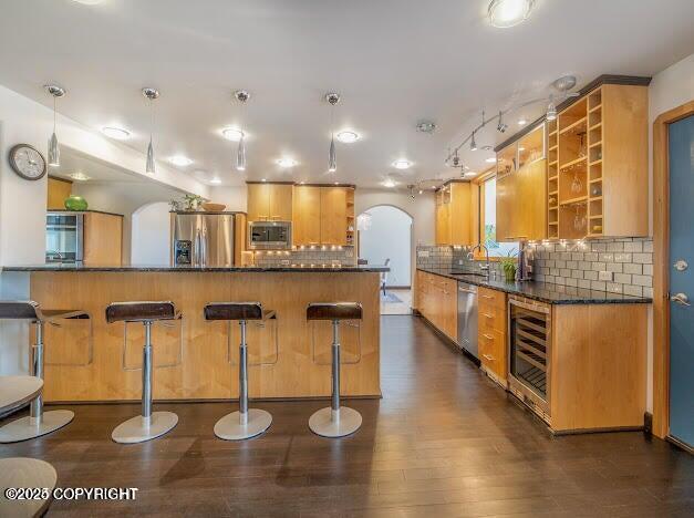 37397 Cetacea Ln, Kenai, AK 99611 - kitchen featuring stainless steel appliances, open shelves, beverage cooler, arched walkways, and a breakfast bar area