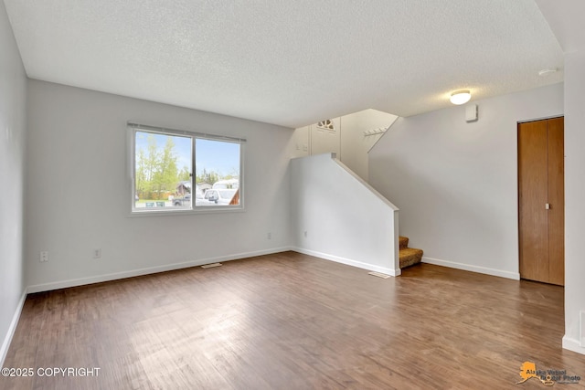 329 Gaylene Cir, Anchorage, AK 99504 - unfurnished living room with a textured ceiling, wood finished floors, stairway, and baseboards