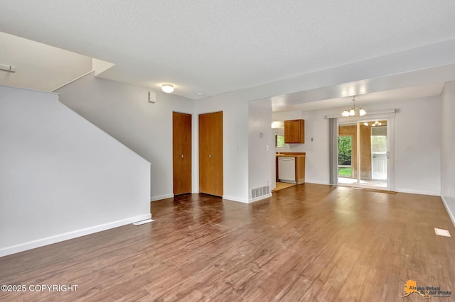 329 Gaylene Cir, Anchorage, AK 99504 - unfurnished living room with wood finished floors, a chandelier, a textured ceiling, and baseboards