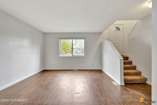 329 Gaylene Cir, Anchorage, AK 99504 - unfurnished living room featuring wood finished floors, a textured ceiling, stairs, and baseboards