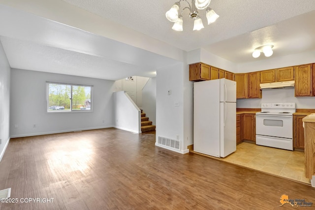 329 Gaylene Cir, Anchorage, AK 99504 - kitchen with white appliances, under cabinet range hood, open floor plan, a chandelier, and brown cabinets