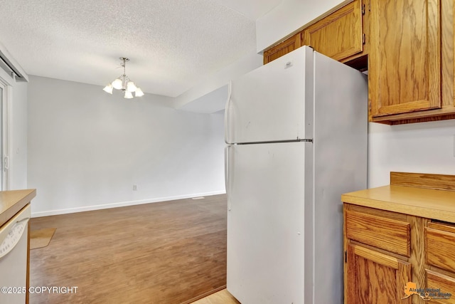 329 Gaylene Cir, Anchorage, AK 99504 - kitchen with white appliances, a chandelier, light wood-style flooring, a textured ceiling, and brown cabinets