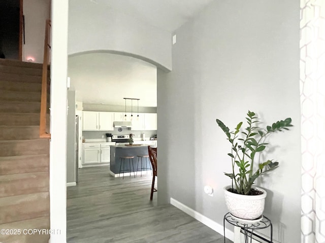 517 Sut Larsen Way, Kodiak, AK 99615 - corridor featuring arched walkways, stairway, dark wood-style floors, and baseboards