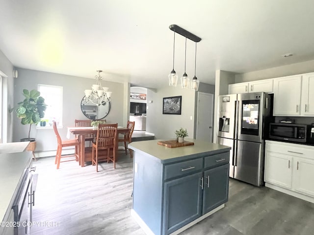 517 Sut Larsen Way, Kodiak, AK 99615 - kitchen featuring stainless steel appliances, baseboard heating, wood finished floors, white cabinets, and a chandelier