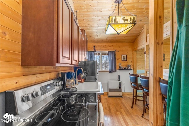 33773 Ruth Glacier Ave, Talkeetna, AK 99676 - kitchen with appliances with stainless steel finishes, wood walls, light wood-type flooring, brown cabinetry, and a sink