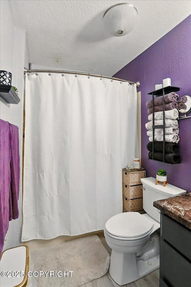 full bathroom featuring toilet, a textured wall, vanity, a textured ceiling, and a shower with curtain