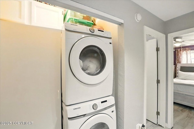 washroom featuring estacked washer and dryer, light wood finished floors, and a ceiling fan