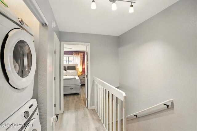 washroom with stacked washer / dryer and light wood finished floors
