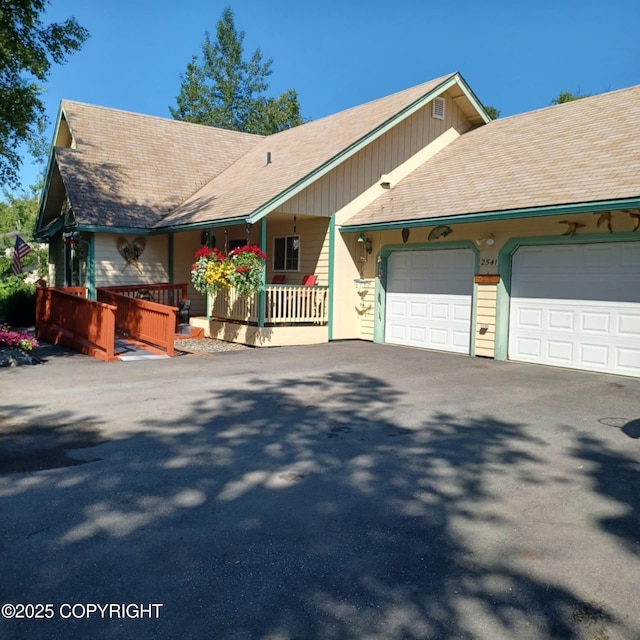 2541 S Teeland St, Wasilla, AK 99623 - view of front of house featuring a garage, a porch, asphalt driveway, and a shingled roof