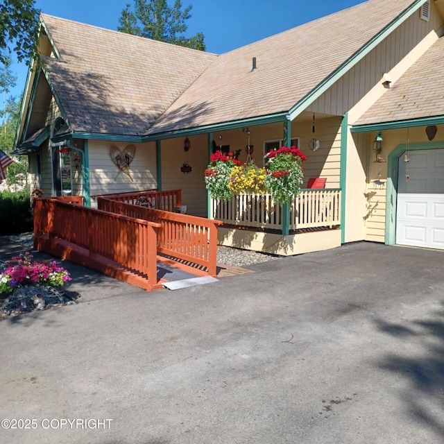 2541 S Teeland St, Wasilla, AK 99623 - view of front of house with covered porch, a garage, roof with shingles, and driveway