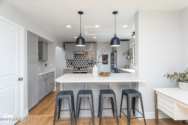 174 E Leota St, Wasilla, AK 99654 - kitchen with gray cabinetry, appliances with stainless steel finishes, a kitchen breakfast bar, backsplash, and a peninsula