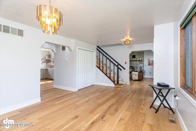 174 E Leota St, Wasilla, AK 99654 - entryway with arched walkways, light wood-style floors, stairway, a chandelier, and baseboards