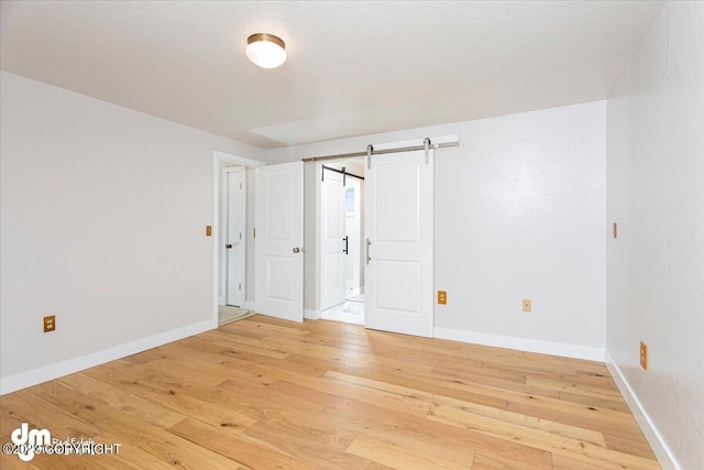 174 E Leota St, Wasilla, AK 99654 - spare room featuring light wood-style flooring, a barn door, and baseboards