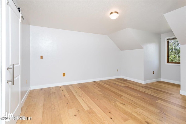 174 E Leota St, Wasilla, AK 99654 - bonus room featuring light wood-type flooring, baseboards, lofted ceiling, and a barn door