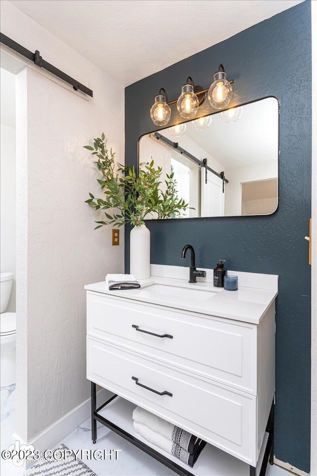 174 E Leota St, Wasilla, AK 99654 - bathroom featuring marble look tile flooring, vanity, toilet, baseboards, and a textured wall