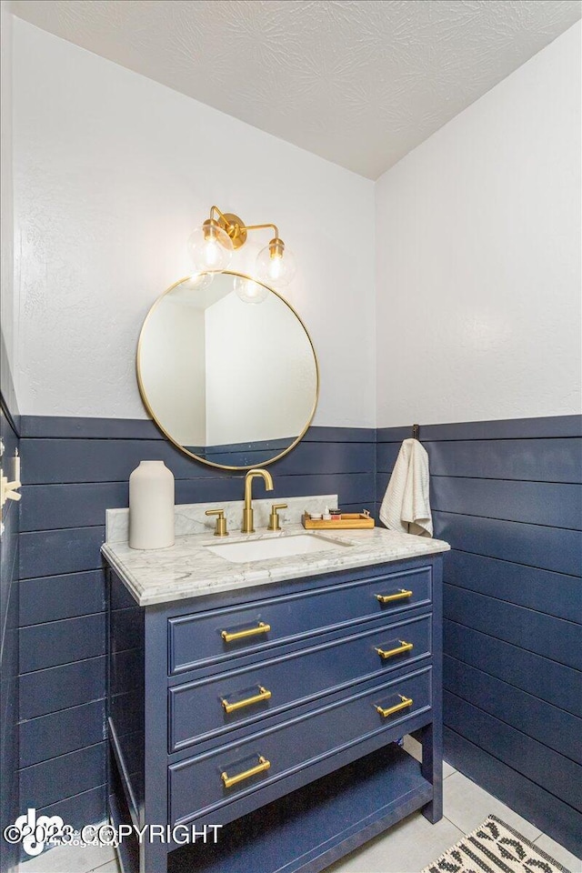174 E Leota St, Wasilla, AK 99654 - bathroom featuring a wainscoted wall, vanity, wooden walls, and tile patterned floors
