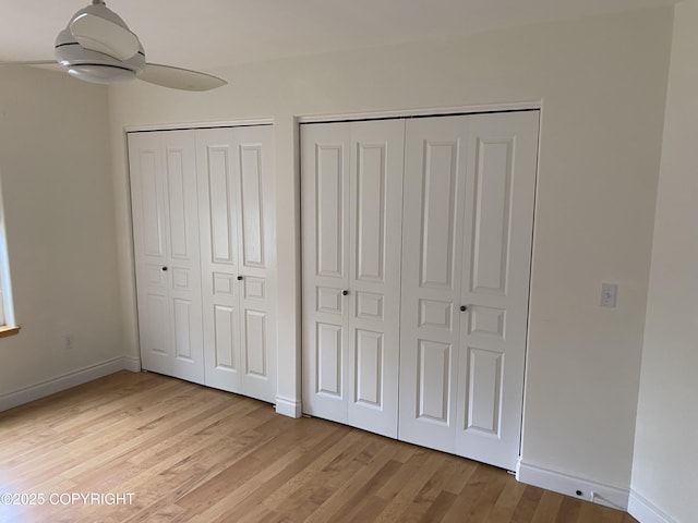 2295 N Filly Cir, Wasilla, AK 99654 - unfurnished bedroom featuring two closets, light wood finished floors, baseboards, and ceiling fan