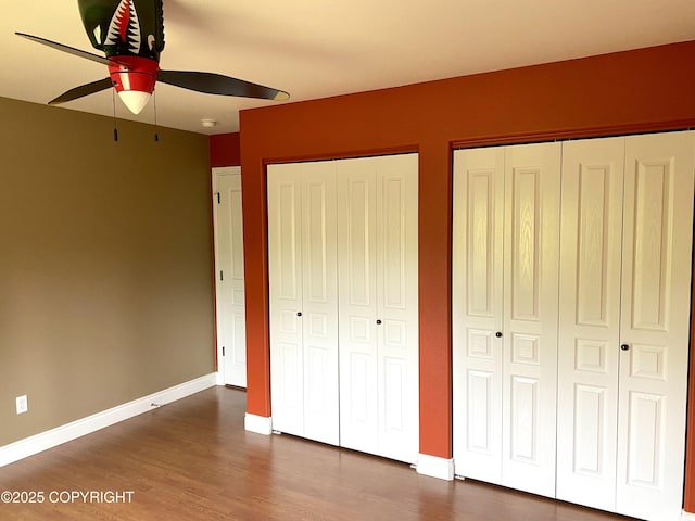 2295 N Filly Cir, Wasilla, AK 99654 - unfurnished bedroom featuring two closets, baseboards, dark wood-style floors, and ceiling fan