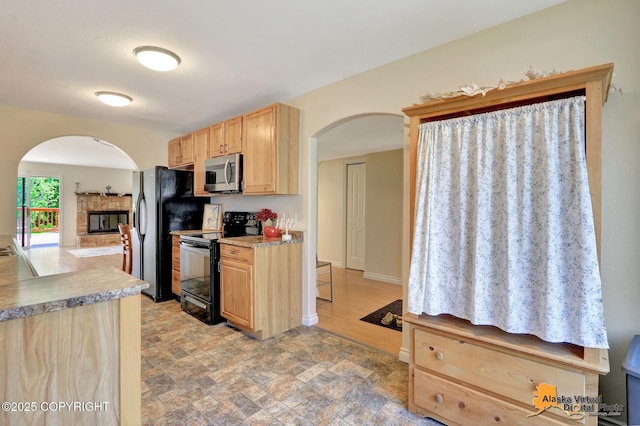 4147 Hampton Dr # 10D, Anchorage, AK 99504 - kitchen featuring black appliances, light brown cabinetry, arched walkways, and stone finish floors