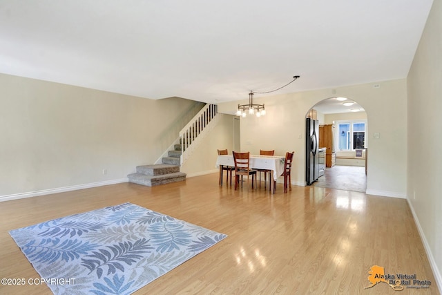 4147 Hampton Dr # 10D, Anchorage, AK 99504 - dining space featuring arched walkways, a chandelier, light wood-style flooring, stairway, and baseboards