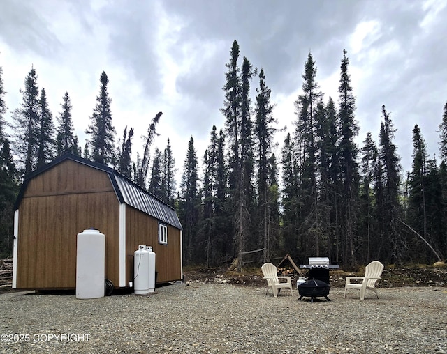 2246 S Fian Dr, Wasilla, AK 99654 - view of outdoor structure featuring an outdoor fire pit and a view of trees